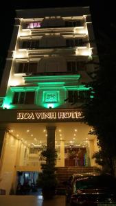 a hotel building with a neon sign in front of it at Khách Sạn Hoa Vinh - Thủ Đức in Ho Chi Minh City