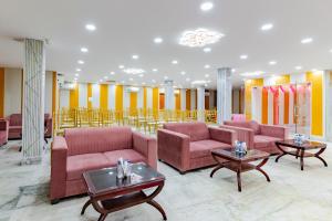 a lobby with pink couches and tables and yellow walls at Treebo Buddha Pride in Patna