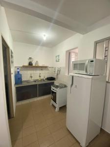 a kitchen with a white refrigerator and a microwave at Ao lado do Hospital Calixto apartamento térreo in Itabuna