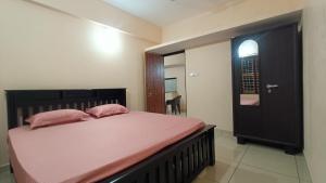 a bedroom with a bed with pink pillows and a door at Gokula Arcade in Subrahmanya