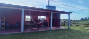a red house with a hammock in a field at AZUL Casa De Campo in Esquina