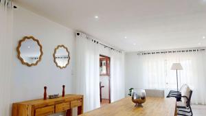 a dining room with a table and two mirrors on the wall at Guernsey Home in Port Shepstone