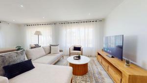 a living room with a couch and a flat screen tv at Guernsey Home in Port Shepstone