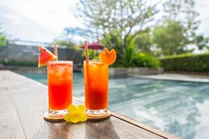 two cocktails on a table next to a swimming pool at Gia Huy Riverside Hotel Hoi An in Hoi An