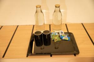 Nillara Kotagiri by Tropic Oasis Hotels في كوتاغيري: زجاجتان زجاجيتان موضوعتان على صينية معدنية على الأرض