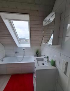 a bathroom with a sink and a tub and a window at Dachgeschoss Harbour Apartments Höri in Moos