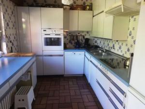 Una pequeña cocina con gabinetes blancos y un fregadero. en Ferienhaus Hebborn, en Bergisch Gladbach