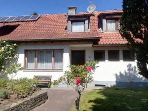 una casa blanca con techo rojo y un banco en Ferienhaus Hebborn, en Bergisch Gladbach