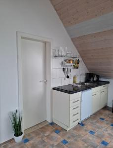 a kitchen with white cabinets and a black counter top at Dachgeschoss Harbour Apartments Höri in Moos +3 photos
