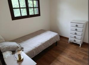 a bedroom with a bed and a dresser and a window at chalet à la campagne in Vielle-Soubiran