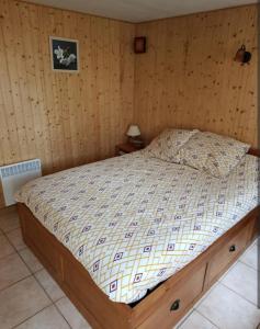 a bed in a room with a wooden wall at chalet à la campagne in Vielle-Soubiran
