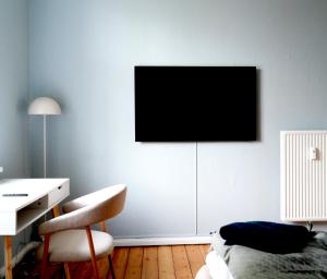 a bedroom with a desk and a television on the wall at Danmarksgade Ensuites in Aalborg