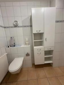een badkamer met een toilet en witte kasten bij Ferienwohnung Ruhrtal in Bestwig