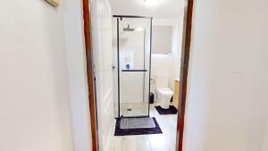 a bathroom with a glass shower with a toilet at Guernsey Flat in Port Shepstone