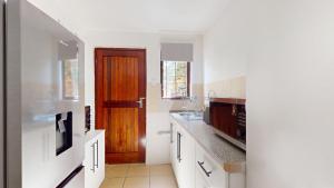 a kitchen with white cabinets and a wooden door at Guernsey Flat in Port Shepstone +2 photos