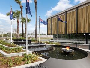 eine Feuerstelle vor einem Gebäude mit Flaggen in der Unterkunft Novotel Sydney Cabramatta in Cabramatta