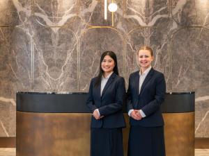 Ein Mann und eine Frau in Anzügen stehen neben einer Wand in der Unterkunft Novotel Sydney Cabramatta in Cabramatta + 99 Fotos