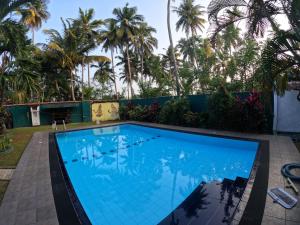 コスゴダにあるSanka Rest Ayurvedic Home Stayのヤシの木が背景に浮かぶスイミングプール +8枚の写真