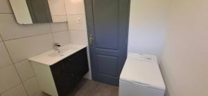 a small bathroom with a sink and a blue door at Le Vallon du Garn - Gîte en pleine nature in Laval-Saint-Roman +3 photos