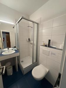 ein Badezimmer mit Dusche, Toilette und Waschbecken in der Unterkunft Hotel-Restaurant Nord Stuv in Cuxhaven