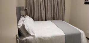 a bed with white sheets and pillows next to a window at Peaceful Casa in Kempton Park