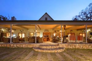 阿多Camp Figtree by The Oyster Collection的一栋带大露台的大房子，露台上摆放着椅子。