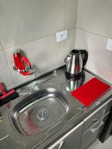 a kitchen counter with a sink and a tea kettle at Panama 90 - Studio - Região Central in Poços de Caldas +11 photos