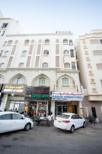 Dos coches blancos estacionados frente a un edificio en Mozna Hostel, en Mascate 14 fotos más