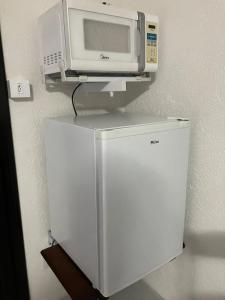 a microwave sitting on top of a refrigerator at Panama 90 - Studio - Região Central in Poços de Caldas