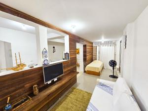 a living room with a television on a wooden wall at CASA COMPLETA 5min DA PRAIA JUQUEHY in São Sebastião