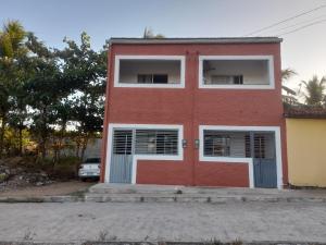 un edificio rojo con ventanas blancas y una puerta roja en Encanto de Tatuamunha, en Porto de Pedras