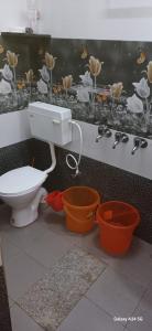 ein Badezimmer mit einem WC und zwei orangenen Eimern in der Unterkunft Vanashree Homestay Galamudi in Sringeri + 6 Fotos