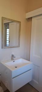 une salle de bains avec un lavabo blanc et un miroir dans l'établissement Kalk Bay Apartment, à Kalk Bay
