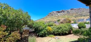 une maison avec une clôture, des arbres et une montagne dans l'établissement Kalk Bay Apartment, à Kalk Bay