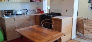 Il comprend une cuisine équipée d'une cuisinière et d'une table en bois. dans l'établissement Kalk Bay Apartment, à Kalk Bay
