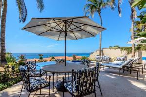 a table and chairs with an umbrella and the ocean at Villa Pura Vida in San José del Cabo
