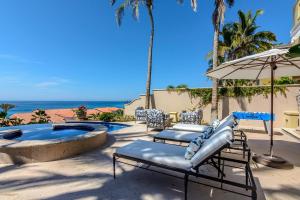a pool with chairs and an umbrella next to the ocean at Villa Pura Vida in San José del Cabo