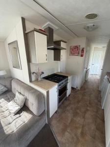 a kitchen with a couch and a stove in a room at Sunnymede D1 - Hot Tub Caravan - Sleeps 10 - Fantasy Island, Ingoldmells - Meadow Lakes Caravan & Lodge Hire in Ingoldmells