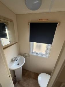 a bathroom with a sink and a toilet and a window at Sunnymede D1 - Hot Tub Caravan - Sleeps 10 - Fantasy Island, Ingoldmells - Meadow Lakes Caravan & Lodge Hire in Ingoldmells