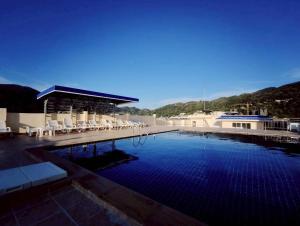 a large swimming pool with chairs and a building at 3-bedroom apartment, Patong, Palm Spring 602 in Patong Beach