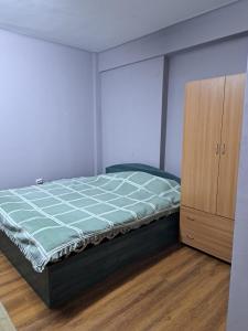 a bedroom with a bed and a wooden cabinet at Garsoniera in inima Targului de Craciun in Craiova