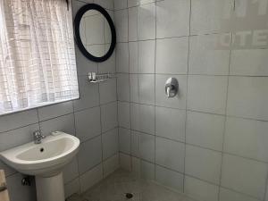 Un baño blanco con lavabo y espejo. en N1 Hotel Samora Machel Harare, en Harare 30 fotos más