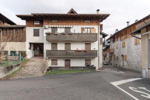 an old building with a balcony on a street at Mansarda di charm Valli di Borzago in Mortaso