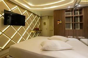 Schlafzimmer mit einem weißen Bett und einem Flachbild-TV in der Unterkunft Golden Motel in Passo Fundo