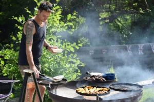a man is cooking food on a grill at The Shire Glamping in Kearsney