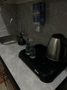 a kitchen counter with a tea kettle and two water bottles at شقق رحابة المكان للشقق المفروشه in Al Kharj