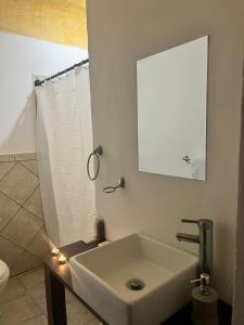 a white bathroom with a sink and a mirror at Antigua Encantó Colonial in Antigua Guatemala