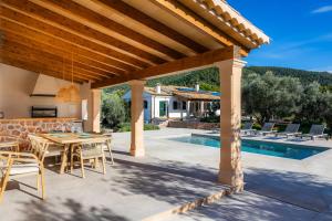 een terras met een tafel en stoelen naast een zwembad bij Ca na Barons in Bunyola