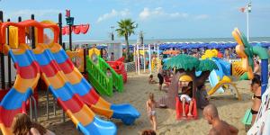 een groep kinderen die spelen op een speeltuin op het strand bij Hotel San Marino in Riccione
