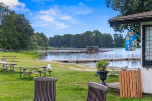 a picnic area with tables and chairs next to a lake at Sjöutsikt Sövde in Sövde